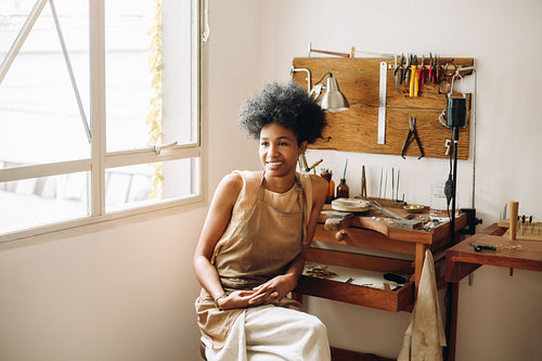 Jewelry artist with apron in studio