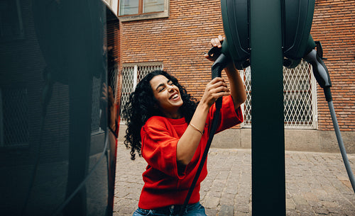 On an urban street, charging keeps a woman and her electric car moving