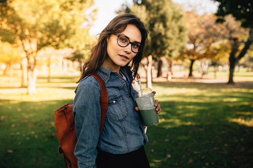 Beautiful woman standing at park with fruit juice