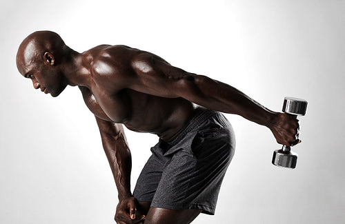 Muscular man shirtless exercising with heavy weights