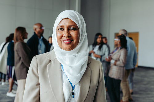Muslim businesswoman in hijab attending a conference with colleagues in the background