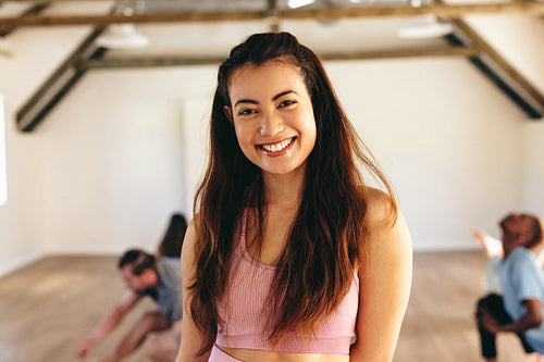 Happy yoga instructor smiling at the camera in a fitness studio