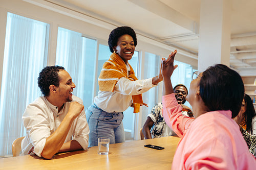 Dynamic startup meeting with diverse team exchanging high-fives