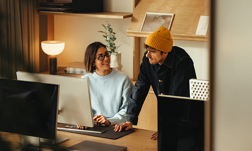 Desk collaboration: two coworkers working together at one computer