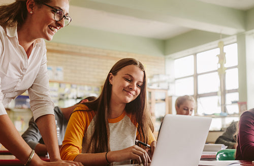 High school teacher helping student in classroom