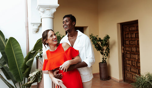 Cheerful couple laughing together on a balcony