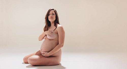 Embracing motherhood: Confident pregnant woman embraces her beautiful baby bump in a studio portrait