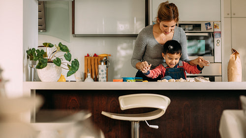 Happy little boy making cookies with mother