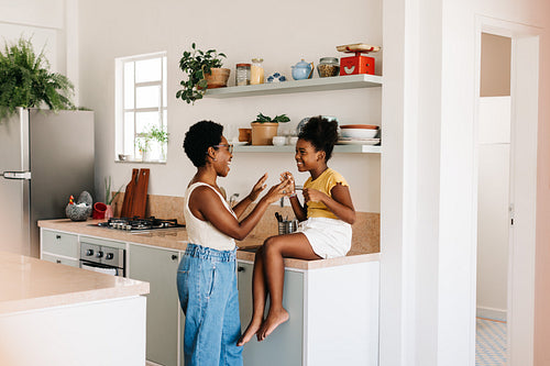 Mother and daughter playing a hand clapping game in the kitchen