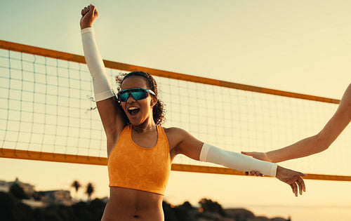 Victorious brazilian athlete celebrates beach volleyball win at sunset