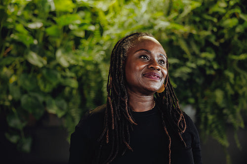 Mature business woman standing in an eco friendly office with a green background