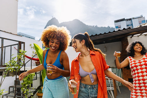 Three women enjoying a pagode gathering in Rio de Janeiro with drinks
