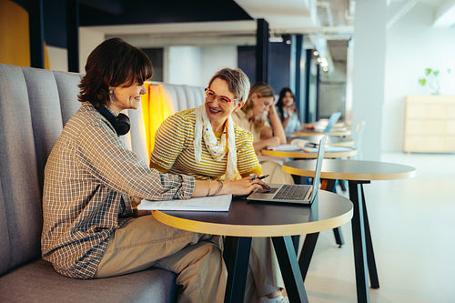 Collaborative learning on campus with engaged students sharing ideas and using laptops in a vibrant educational environment