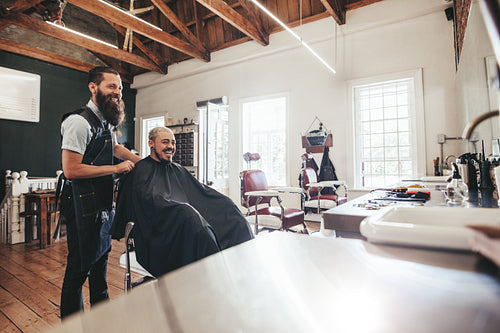 Hairdresser with client sitting at salon and smiling