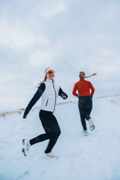Women are running together through winter snow for outdoor fitness