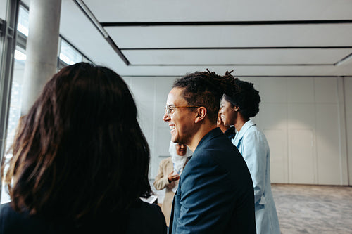 Happy young businessman with dreadlocks talking with colleagues in a professional setting