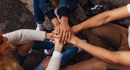 Group of friends sitting together stacking their hands on one another