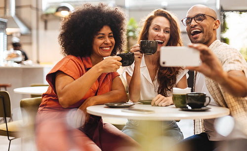 Three happy friends taking a selfie and having fun on a coffee break