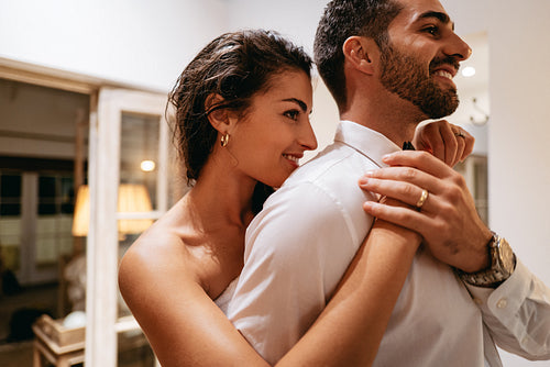 Woman fixing her husband's bow tie in a hotel room