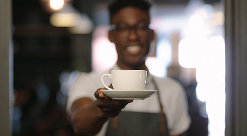Café owner at his coffee shop holding a coffee cup