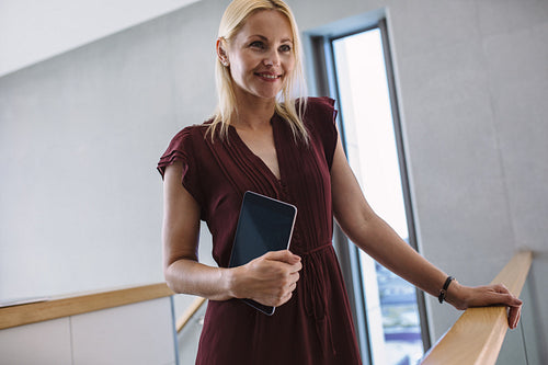 Woman in office corridor with digital tablet