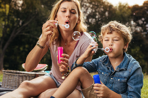 Little boy makes soap bubbles with her mom in the park