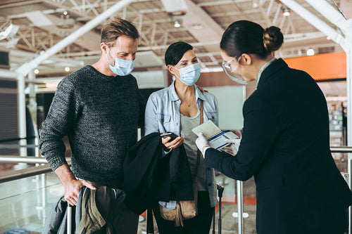 Airline attendant checking boarding pass of tourist couple