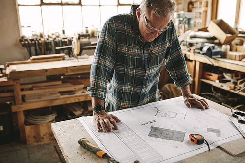 Carpenter checking the building plans before starting