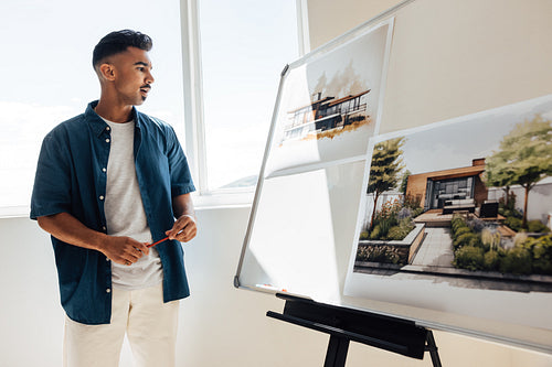 Young architect presenting contemporary house designs on whiteboard during a design meeting