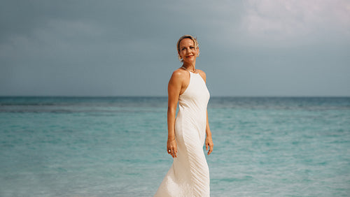 Woman in white dress standing on a tropical beach with blue waters