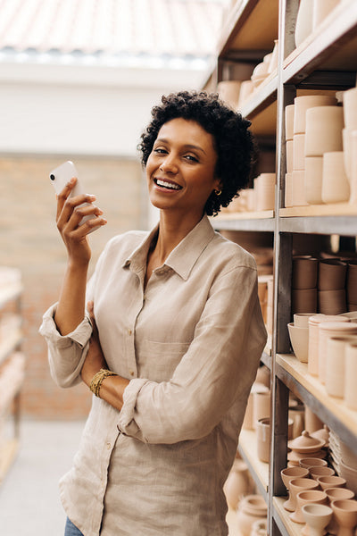 Female entrepreneur smiling at the camera in her ceramic shop