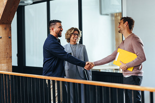 Successful business men shaking hands over a promotion in an office