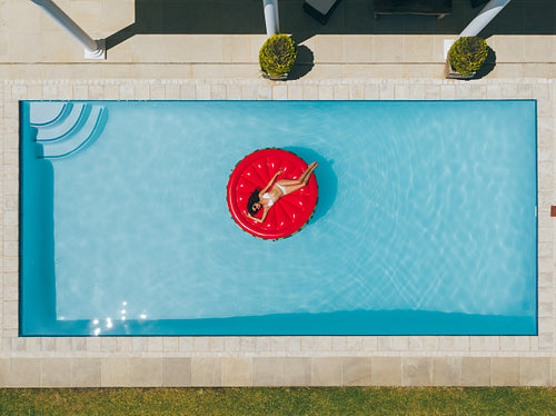 Woman floating on inflatable mattress in pool