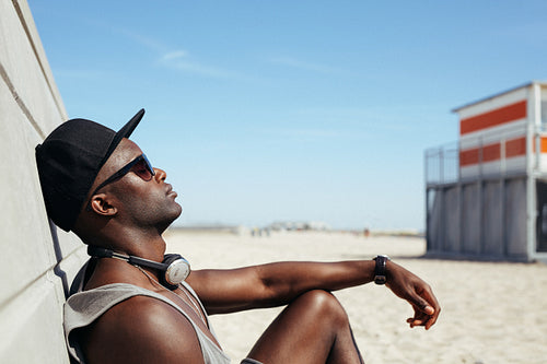Relaxed african man leaning to a wall at beach