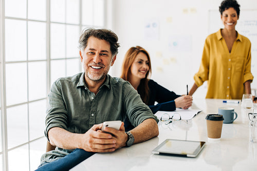 Mature business man sitting in a boardroom meeting with his team