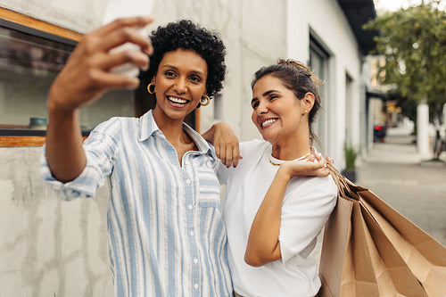 Cheerful female friends taking a selfie together after shopping