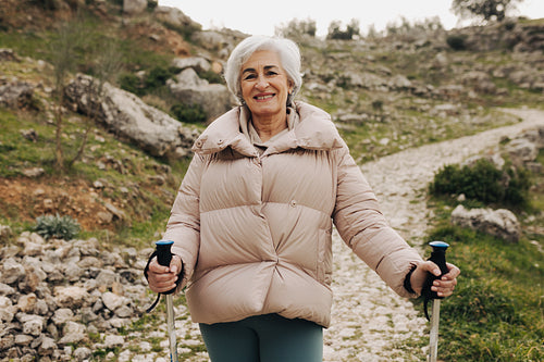 Happy senior woman smiling at the camera while hiking outdoors