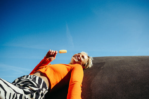 Young woman enjoys a popsicle under clear blue sky outdoors