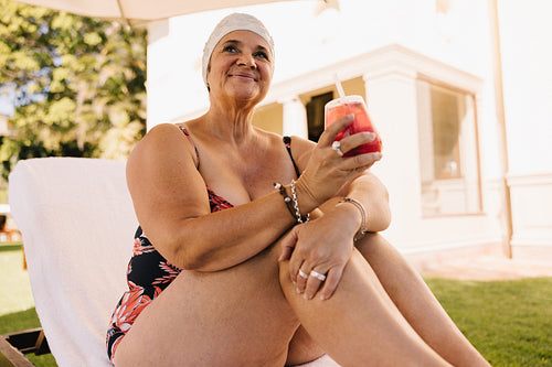 Carefree senior woman relaxing on a lounger at a tropical spa resort