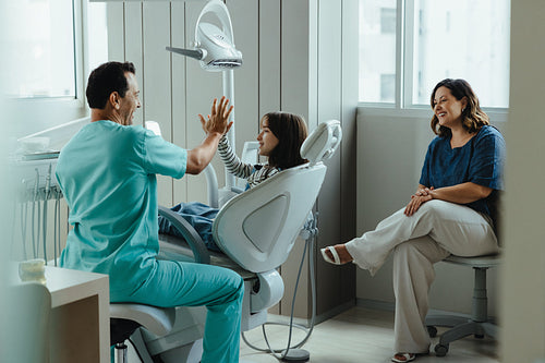 Successful dental checkup with a high five between dentist and child