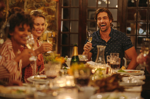 Cheerful young people having drinks at dinner party