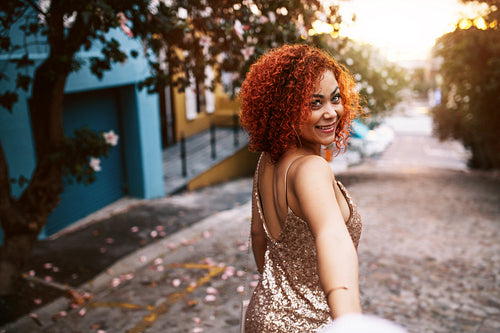 Close up of a young woman looking back while walking on a deserted road.