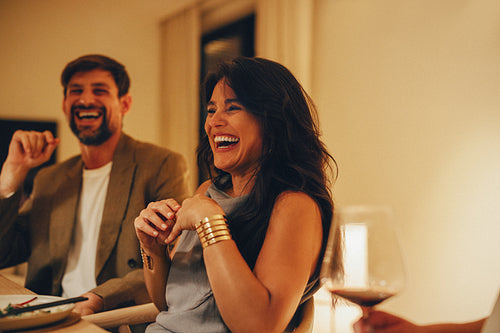 Friends enjoying laughter during an intimate dinner at home