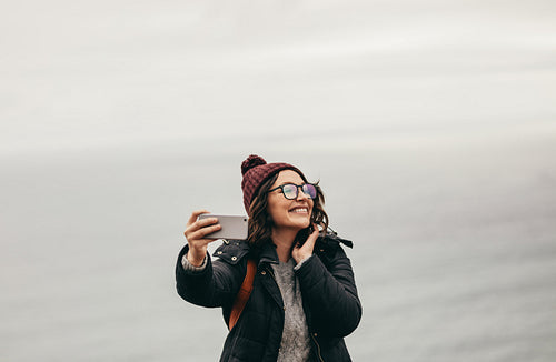 Smiling female traveler taking a selfie against ocean