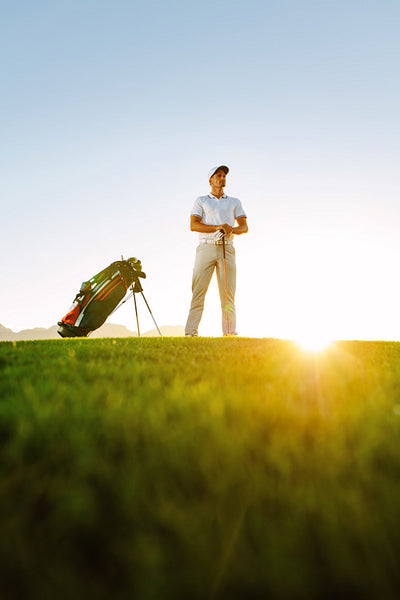 Professional golfer standing on field at sunset