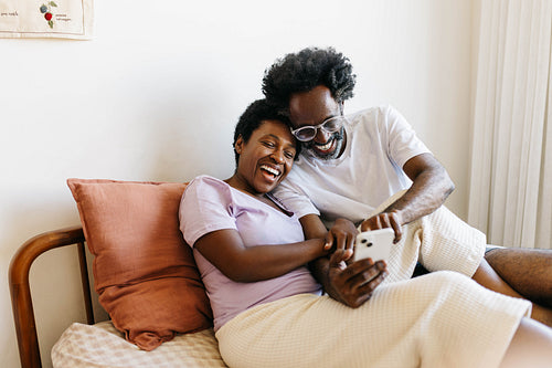 Mature couple browsing a smartphone in their bedroom