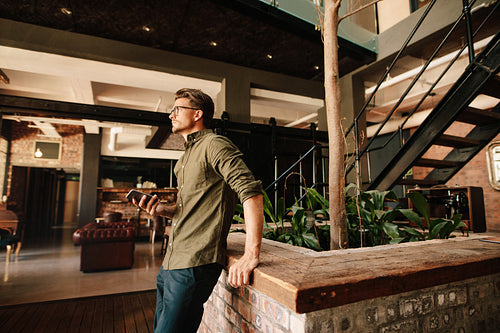 Young man standing in modern office looking away 