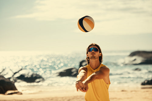 Athlete spikes ball on coastal beach court at sunset