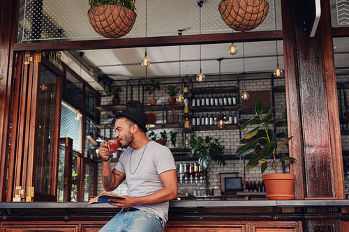 Happy young man at cafe with a book and drinking coffee