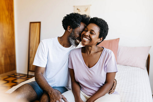 Romantic black couple laughing and relaxing on a bed